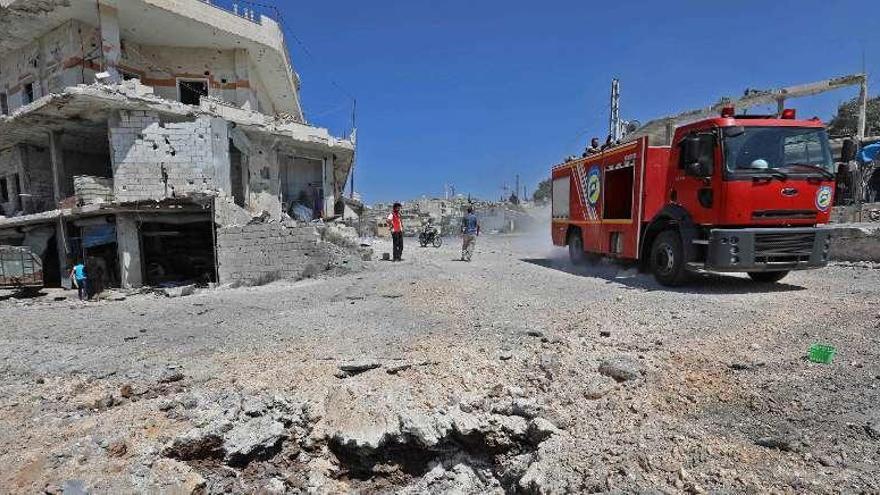 Un coche de bomberos circula junto a un inmueble destruido, en Idlib, en un bombardeo atribuido a Rusia. // AFP