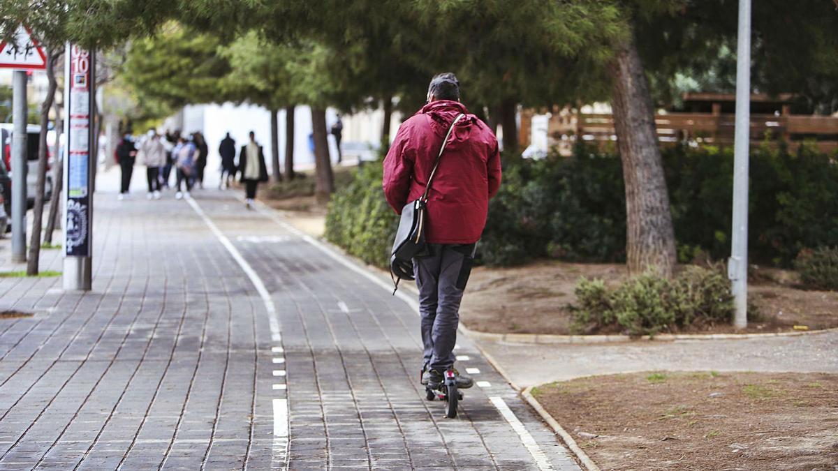 Un hombre transita con su patinete eléctrico, y sin casco, por una zona prohibida, al tratarse de una acera bici de Alicante.