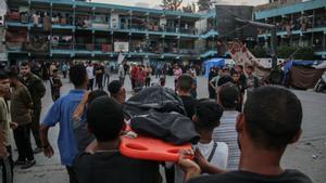 Un grupo de palestinos transportan el cadáver de una víctima del bombardeo en una escuela de la UNRWA.