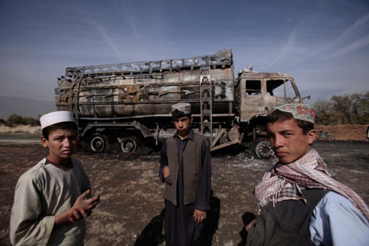 Joves afganesos posen davant d’un camió de combustible que ha explotat a la província de Parwan, al nord de Kabul (Afganistan).