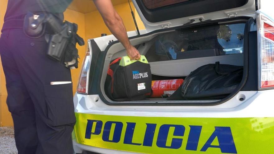 Un agente manipula el desfibrilador de un coche patrulla.