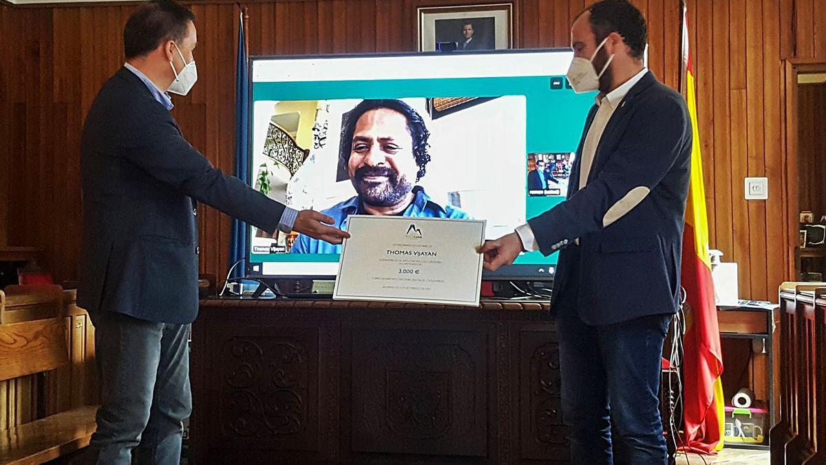 Román Benito –a la izquierda– e Iván Allende sostienen el diploma del premio económico del XXX Memorial “María Luisa”, ayer, durante la videoconferencia con Thomas Vijayan, que aparece en la pantalla. | Memorial María Luisa