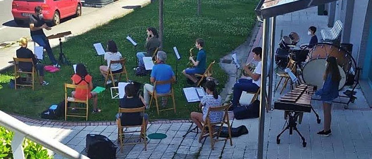 Los alumnos de la banda de la Escola de Música ensayan al aire libre. / E.M.