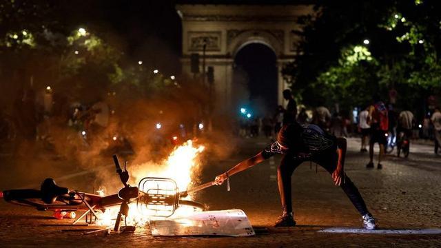 Una bicicleta cremant davant l’Arc de Triomf de París, en els disturbis durant les celebracions per la victòria del PSG. | KENZO TRIBOUILLARD / AFP
