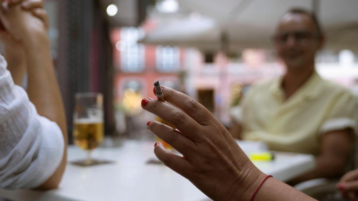 Una mujer fumando en una terraza