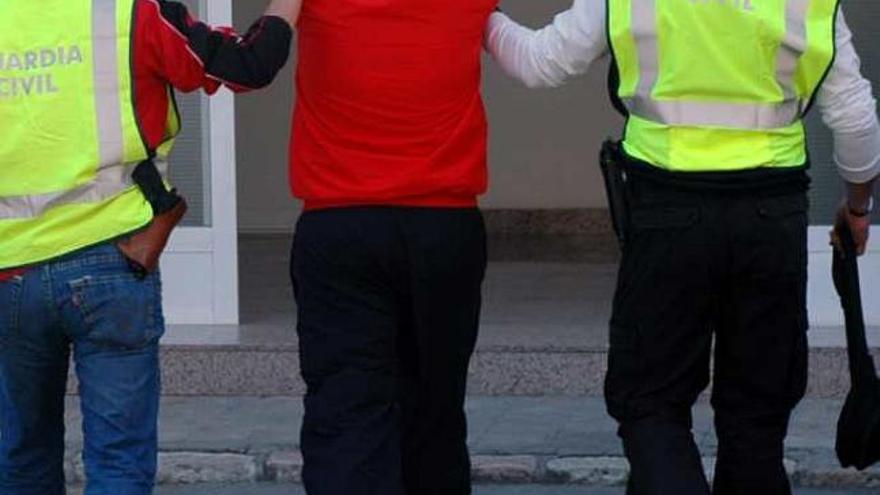 Dos agentes conducen a uno de los detenidos al cuartel.