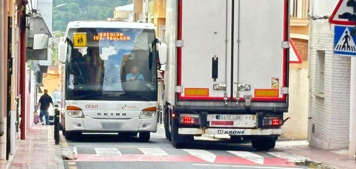 Un autobús escolar y un camión pasan rozándose por la travesía urbana