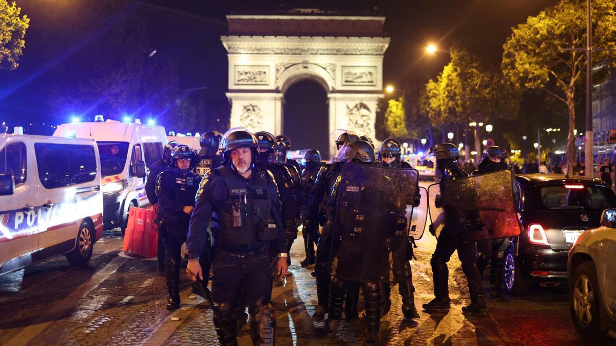 Antidisturbios de la policía francesa patrullan frente al Arco de Triunfo, en los Campos Elíseos, este sábado por la noche.