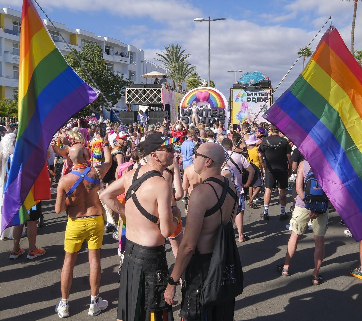 Dos personas se miran mientras portan la bandera del colectivo.