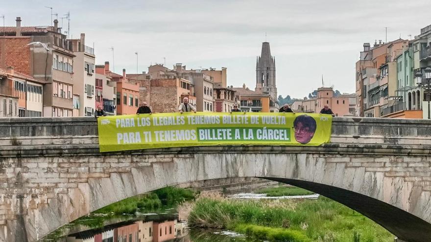 Simpatitzants i militants de Vox aguanten una pancarta al pont de Pedra en contra del retorn de Carles Puigdemont