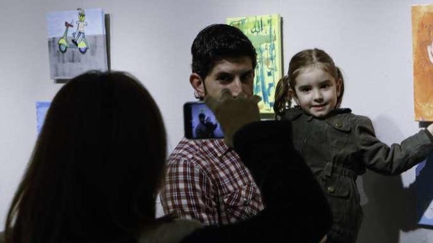 Ana Silvarrey, en brazos de su padre, ante su obra en la exposición.