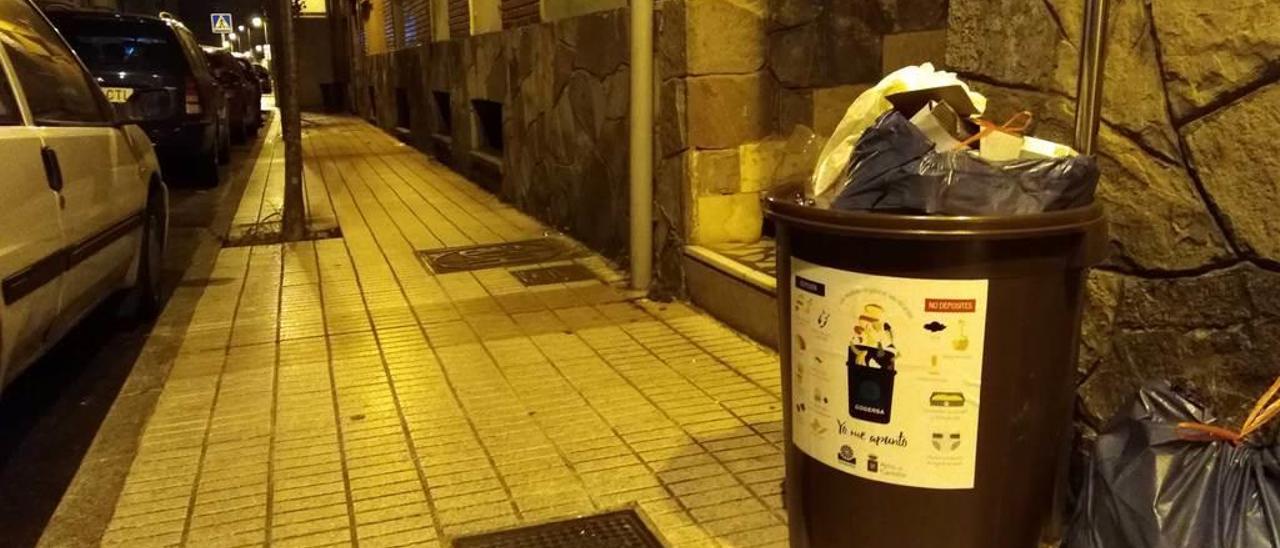 Un cubo marrón, lleno con todo tipo de residuos, en una calle de Candás.