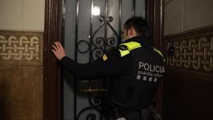 Un agente de la Guardia Urbana llama a un domicilio tras recibir el aviso de un vecino, en Barcelona.