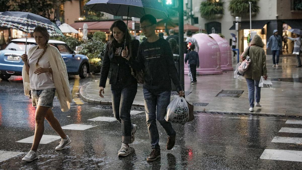 Ciudadanos se protegen de la lluvia en el Passeig des Born de Palma