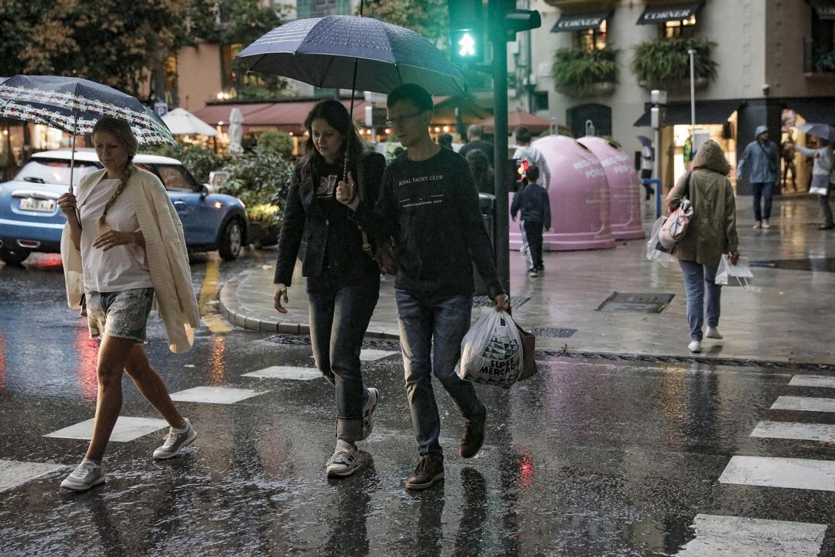 Ciudadanos se protegen de la lluvia en el Passeig des Born de Palma