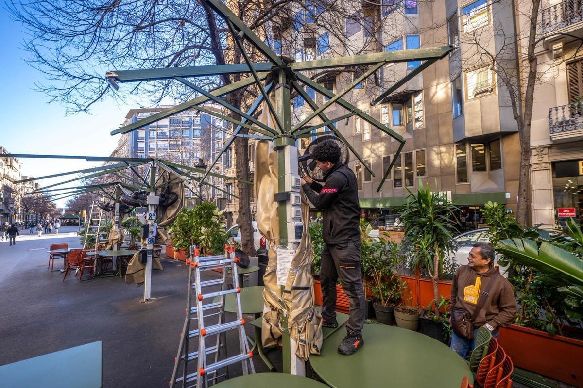 Unos operarios desmontan unos toldos arrasados por el vendaval en un restaurante de rambla de Catalunya, en Barcelona.