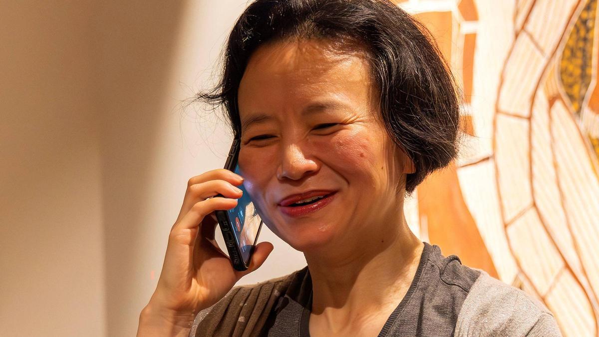 La periodista australiana Cheng Lei habla por teléfono a su llegada al aeropuerto de Melbourne, tras ser liberada por las autoridades chinas.