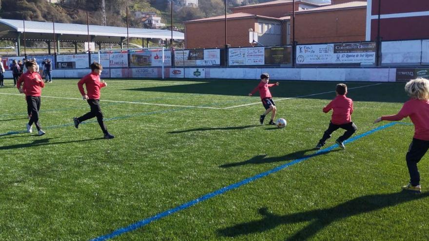 Un grupo de niños jugando en el renovado campo de fútbol de Los Llerones, en Sama. | M. Á. G.