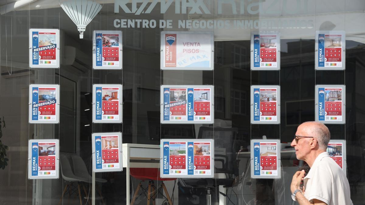 Un vecino camina delante del escaparate de una inmobiliaria de A Coruña.