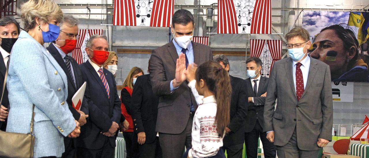 Sánchez saluda a una niña acogida en la Ciudad de la Luz en presencia de Puig