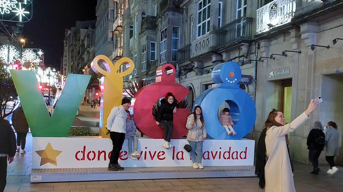 Una familia sacándose una foto en el panel de &quot;Vigo, donde vive la Navidad&quot; de Urzáiz.