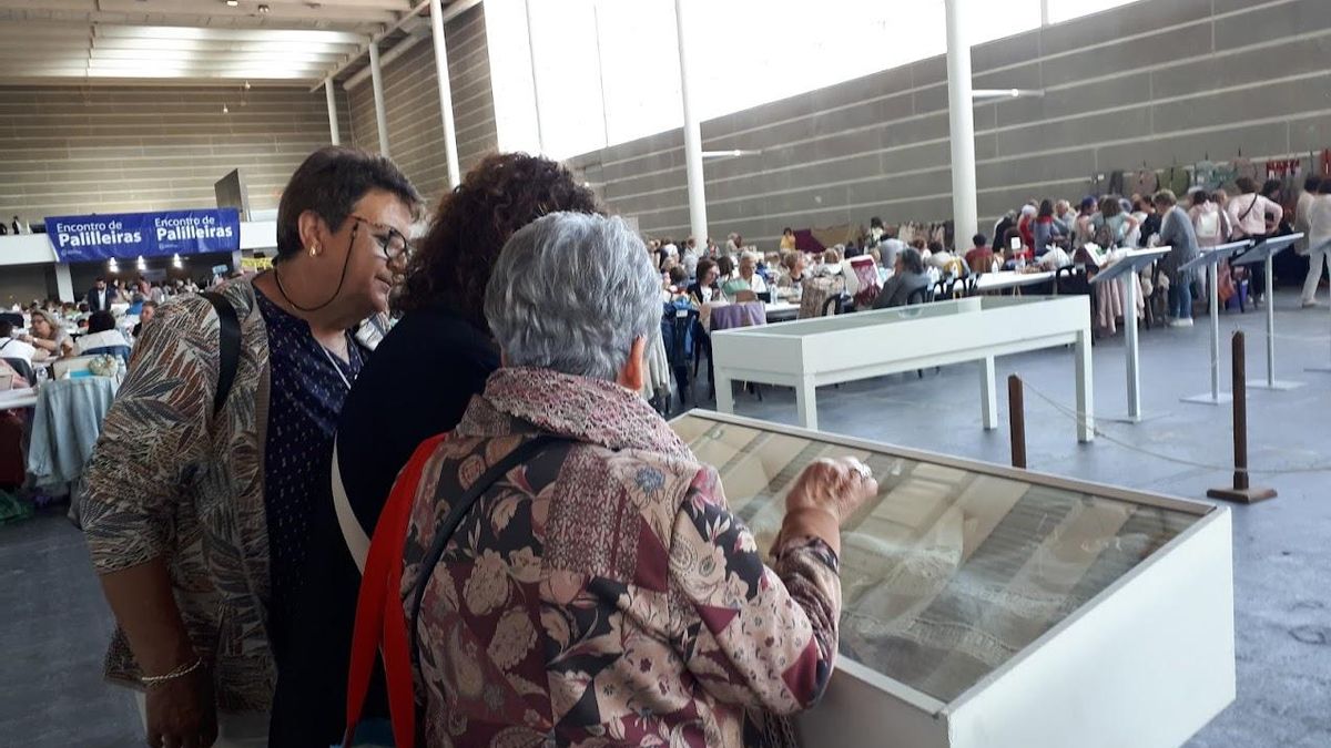 Asistentes al Encontro de Palilleiras que se celebra este domingo contemplan una vitrina con encajes.