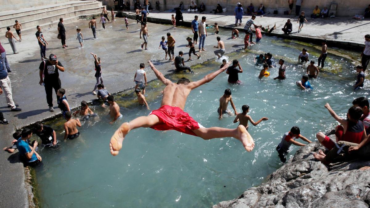 Un niño salta a una piscina de Rayy, en Irán.