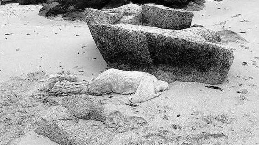 El cadáver, en el lugar en que apareció, varado entre rocas en la playa de A Illa en A Pobra. / la opinión