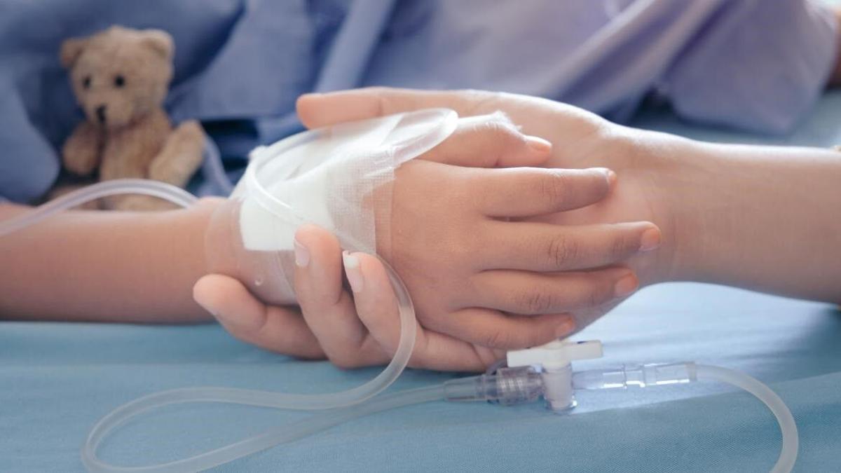Una madre sujeta la mano de su hijo, un menor con cáncer infantil.