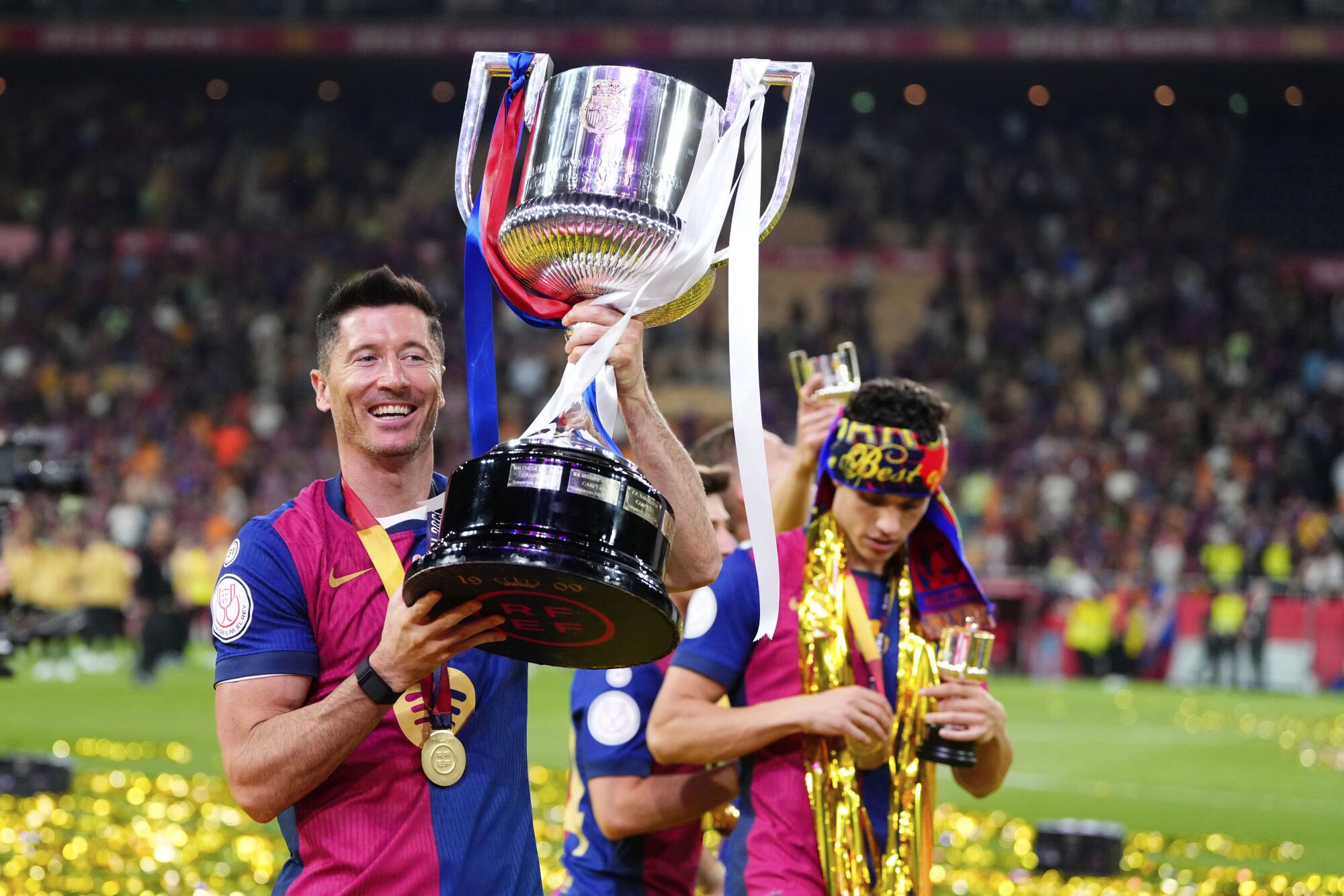 Barcelona's Robert Lewandowski lifts the trophy after winning the Spanish Copa del Rey final soccer match between Barcelona and Real Madrid at Estadio de La Cartuja stadium in Seville, Spain, Sunday, April 27, 2025. (AP Photo/Jose Breton)