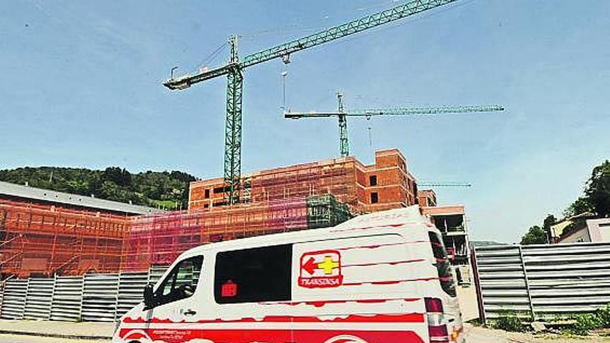 Una ambulancia circula por delante de las obras de construcción del nuevo Hospital Álvarez-Buylla de Mieres.