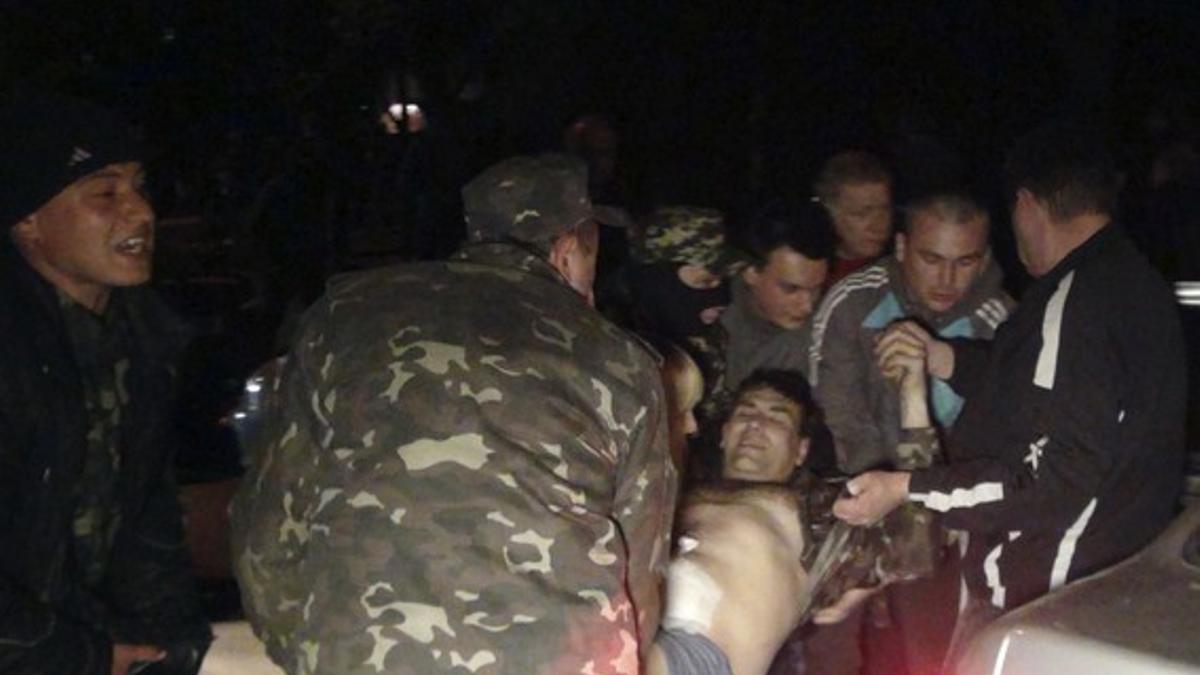 Un grupo de ciudadanos traslada a una persona herida durante el asalto de tropas prorrusas al cuartel de Mariupol, el miércoles por la noche.