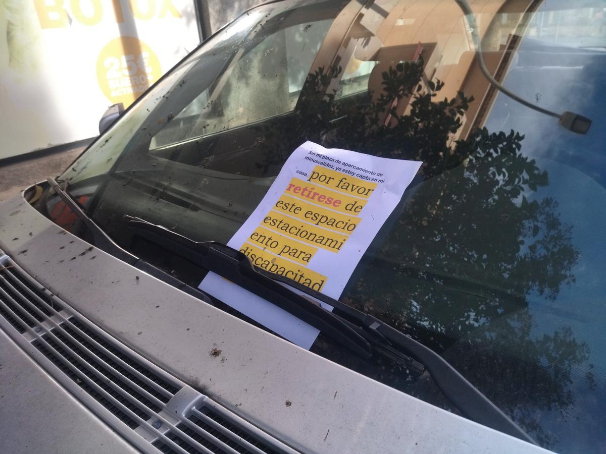 Letrero colocado en un coche aparcado en una plaza para personas con movilidad reducida