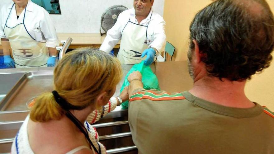 Los voluntarios Pilar García y Juan Carrión atienden a dos usuarios en el comedor.