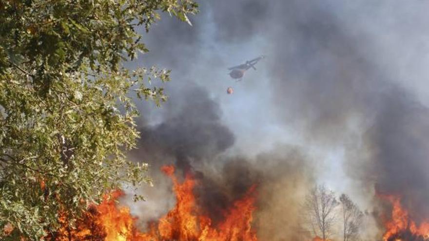 Un helicóptero descarga agua sobre el incendio originado anteayer en Asturianos.