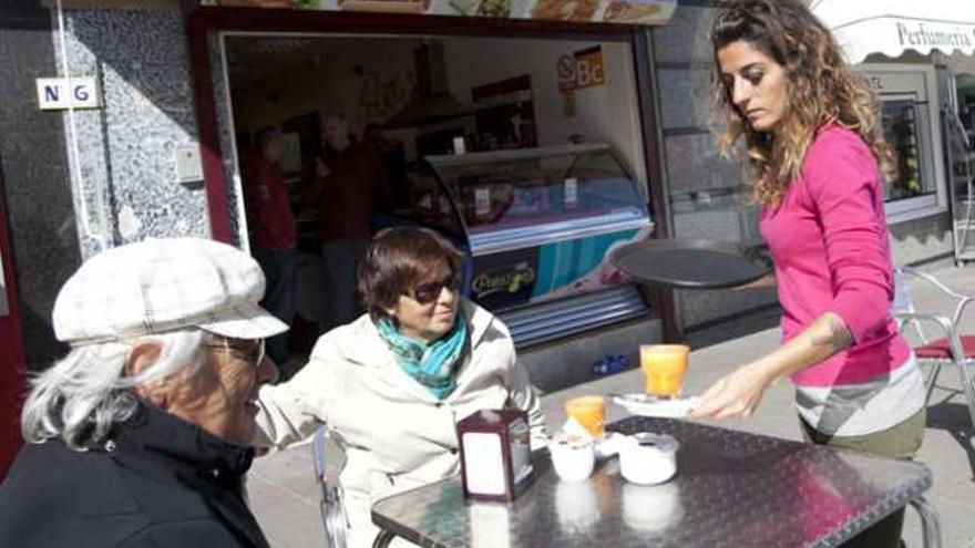 La camarera italiana Valentina Vinchi atiende a unos clientes en una cafetería de Corralejo, ayer. | fuselli