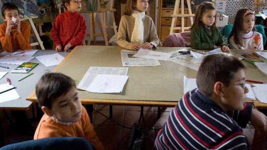 Los menores participantes en el taller atienden las explicaciones para la elaboración de un títere