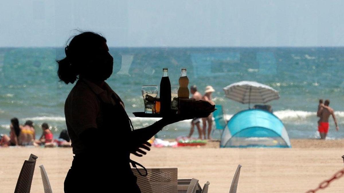 Una camarera lleva bandeja con bebidas en un restaurante.