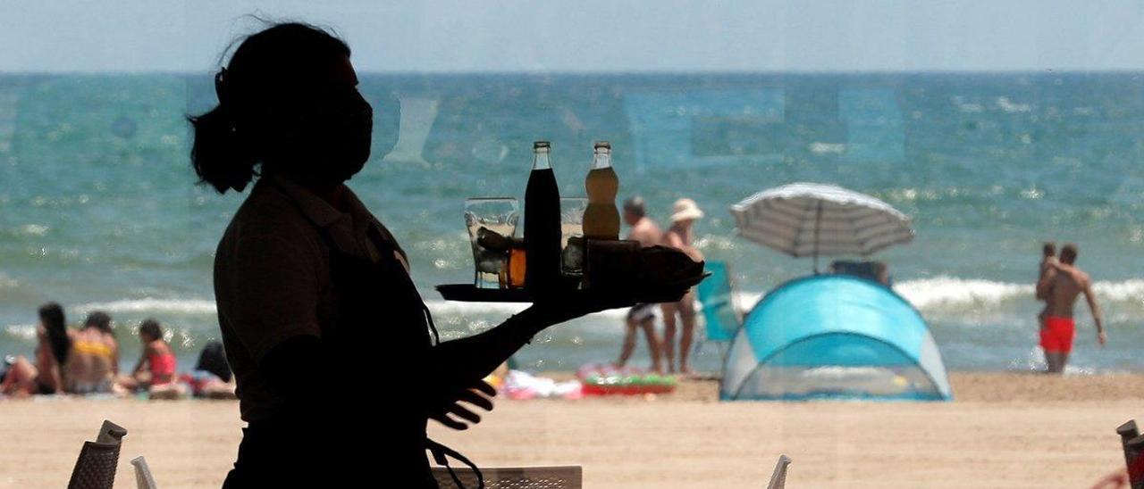 Una camarera lleva bandeja con bebidas en un restaurante.