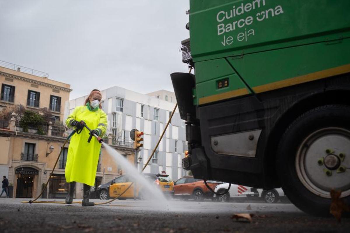 Una trabajadora de la limpieza riega una calle con una manguera, a 10 de enero de 2024, en Barcelona