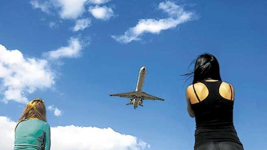 Un avión sobrevuela el cielo de Mallorca ante la mirada de dos mujeres.