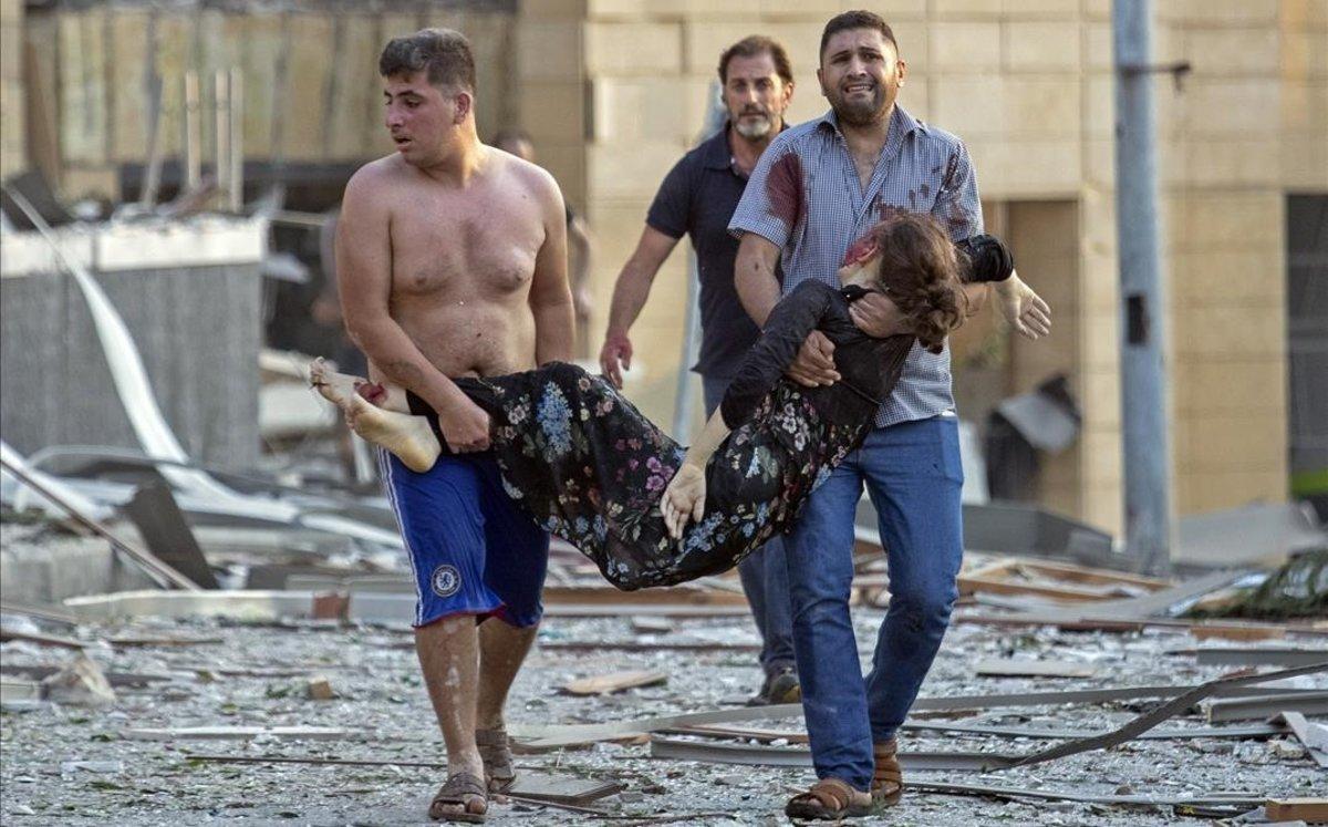 Una mujer es evacuada de la zona de la explosión en Beirut.