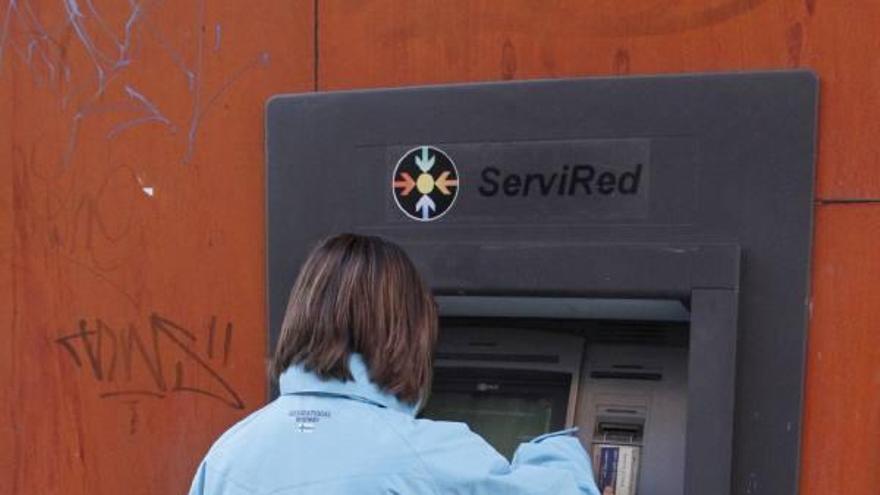 Una joven extrae dinero de una entidad bancaria de la capital.