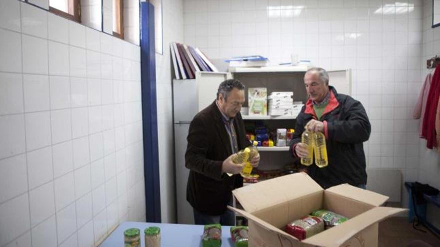 Herminio Torre y Joaquín Arias empaquetan alimentos para familias necesitadas en la sede vecinal de La Camocha.