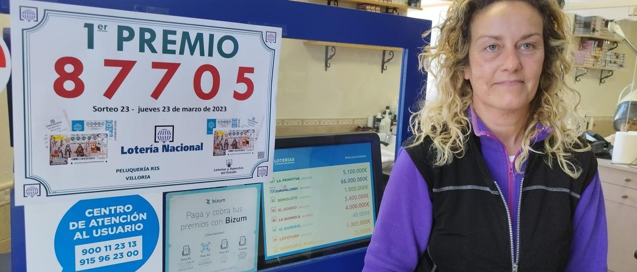 Raquel Iglesias, en su peluquería y administración de Lotería, junto a un cartel con el número premiado. | D. O.