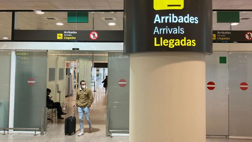 Un senyal de la zona d&#039;Arribades amb un passatger arrossegant una maleta de fons a l&#039;Aeroport del Prat el 23 de novembre