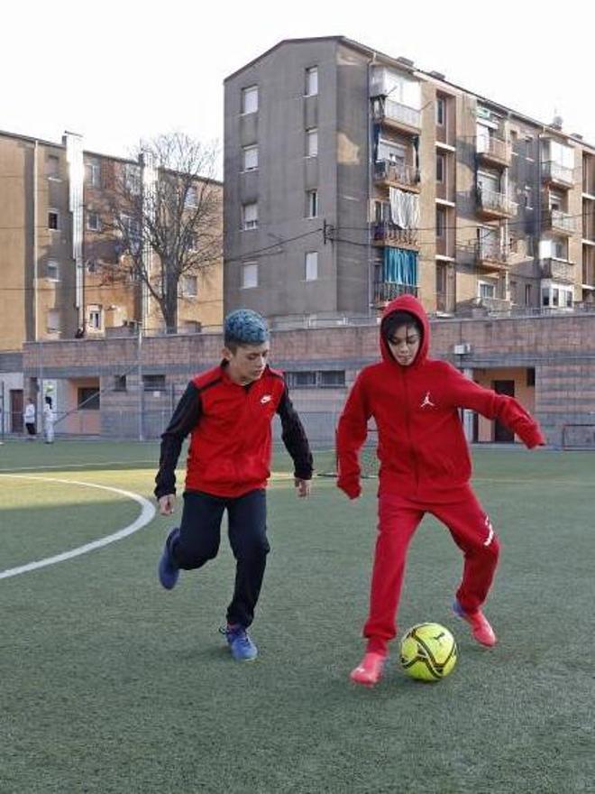 Dos nens entrenant al camp de Vila-roja, davant de blocs de pisos del barri.