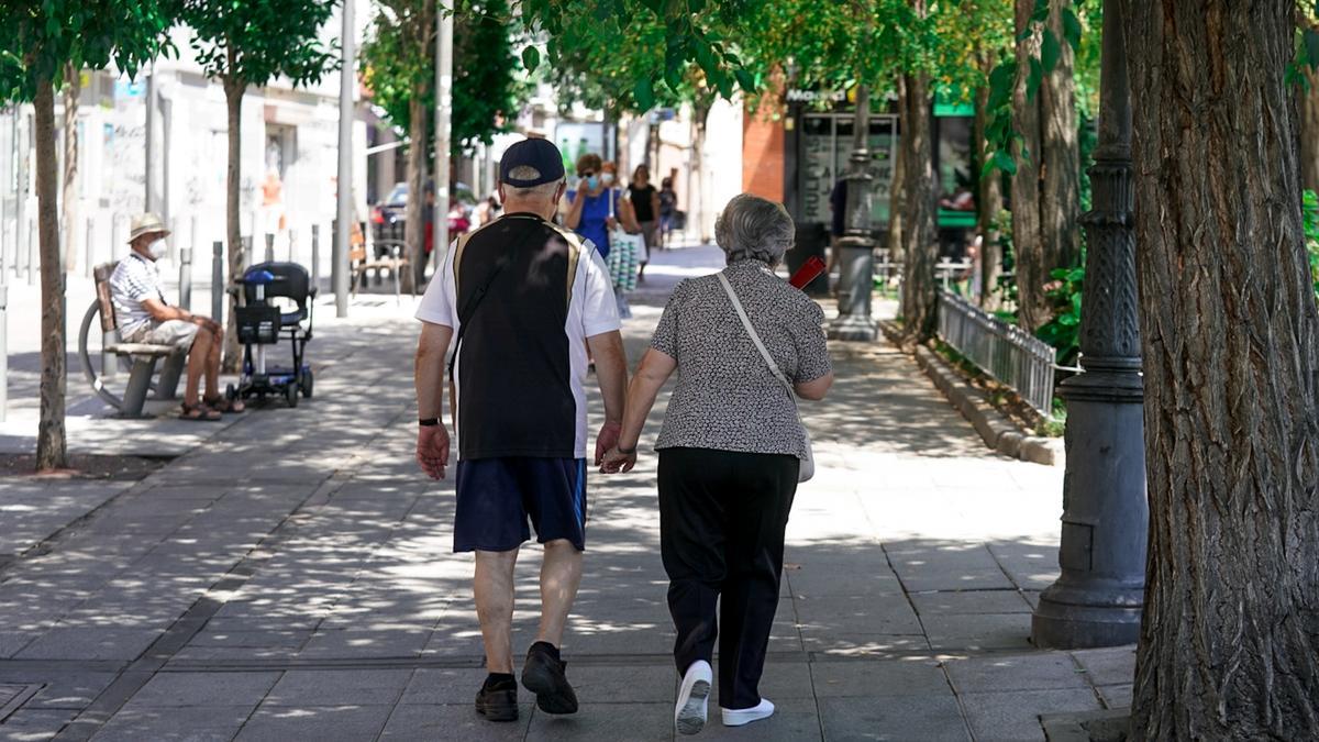 Una pareja de ancianos caminando por la calle cogidos de la mano.