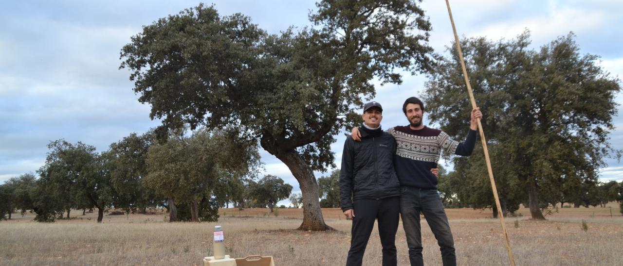 Los hermanos San Martín, en la dehesa con una botella del zumo de bellota.