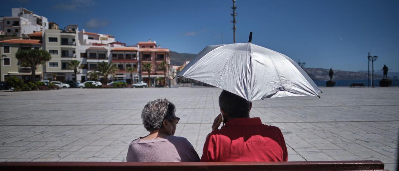 Dos personas mayores en un banco de la plaza de la Basílica de la Patrona de Canarias, en el municipio de Candelaria.